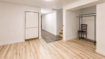 A room with a wooden floor, a white door, and a black metal rack.