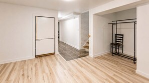 A room with a wooden floor, a white door, and a black metal rack. - 5BR Group House - Brooklyn Center - Sleeps 10 (Minneapolis)