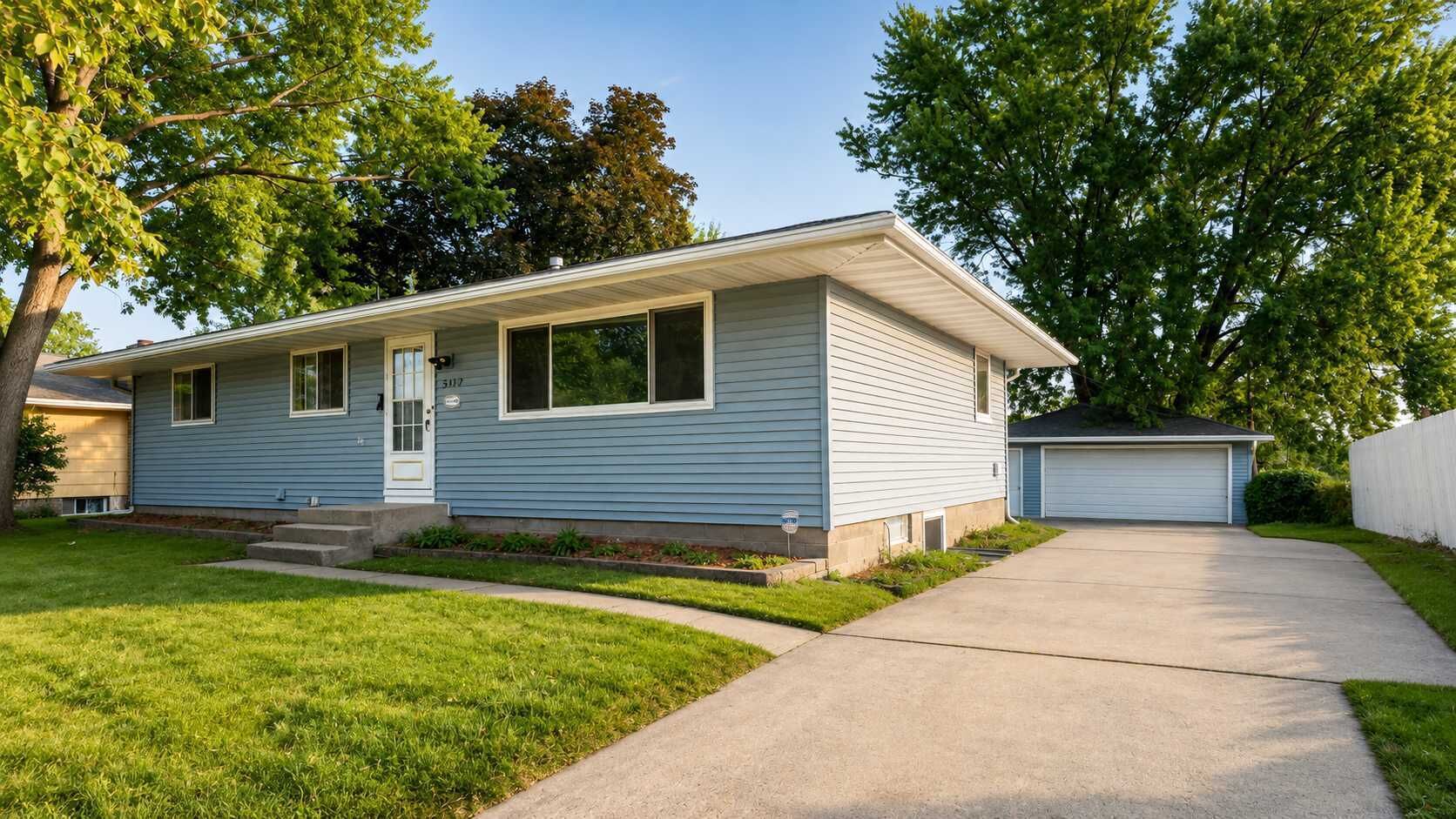 A single-story house with a front porch, a garage, and a well-maintained lawn.