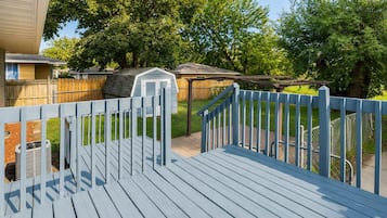 A wooden deck with a blue railing, a small shed, and a chain-link fence in a residential backyard.