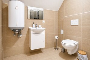 Un baño moderno con calentador de agua instantáneo, un lavabo, un inodoro y un espejo.