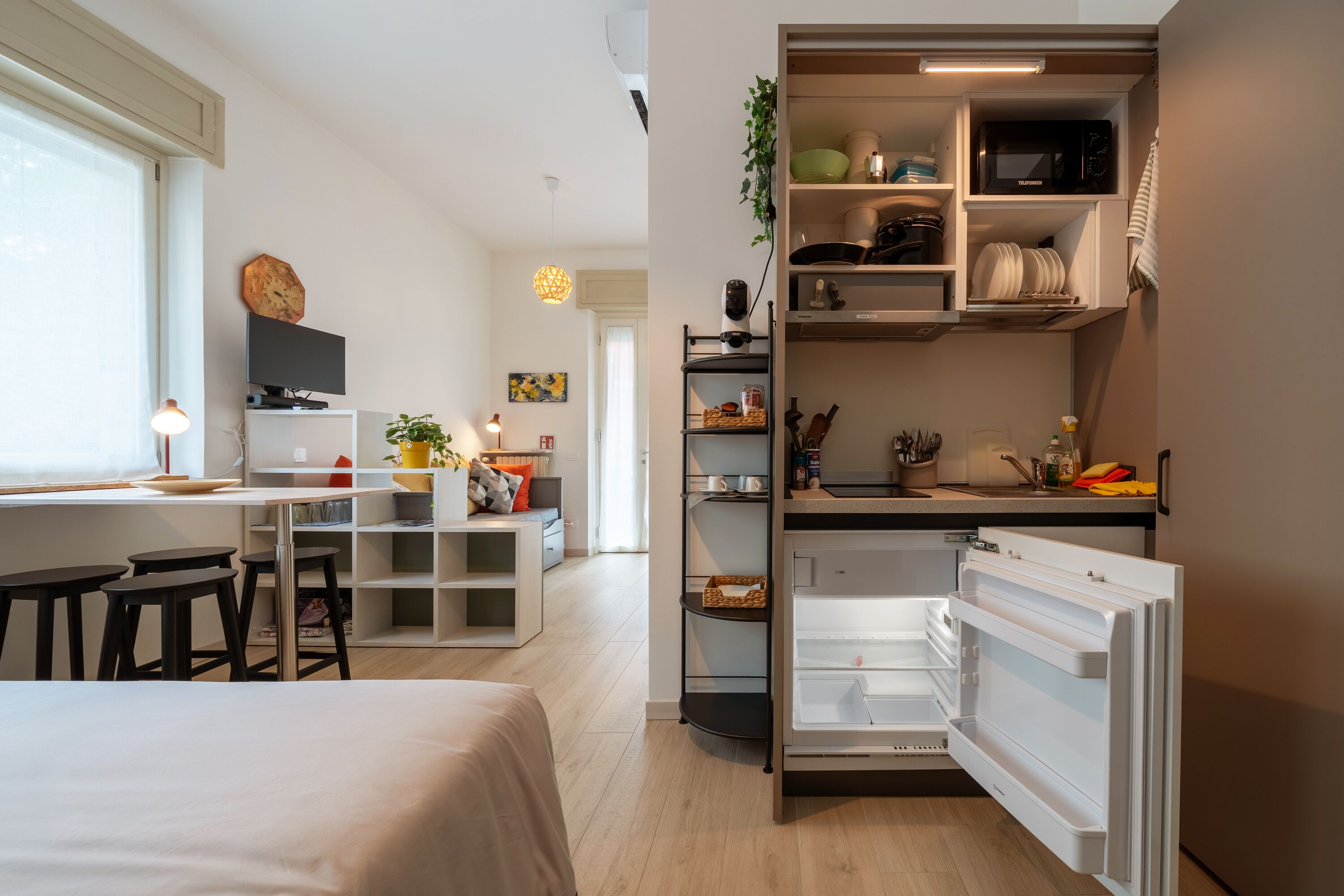 Un espacio habitable compacto con kitchenette, comedor y dormitorio.