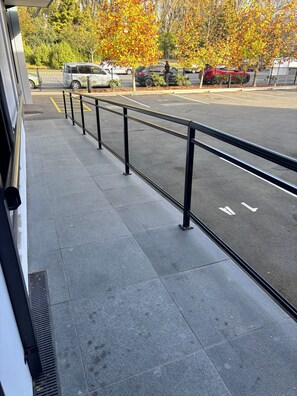 Un parking doté d’une allée piétonne pavée et d’une rambarde en métal.