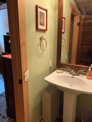 A bathroom with a white sink, a mirror, and a framed picture on the wall. - 4-bedroom farmhouse in beautiful Hurleyville with AC comfort (Hurleyville)