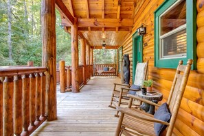 A wooden cabin with a porch, a bench, and a window with a view of the forest. - 2 King Ensuites on first level | Private with easy access | Outdoor Fireplace | Hot Tub | Game Room (Sevierville)