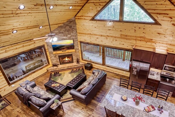 A cabin interior with a fireplace, seating area, and kitchen. - 2 King Ensuites on first level | Private with easy access | Outdoor Fireplace | Hot Tub | Game Room (Sevierville)