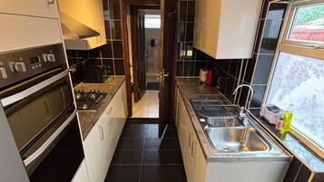 A modern kitchen with a central island, stainless steel appliances, and black tiled flooring.