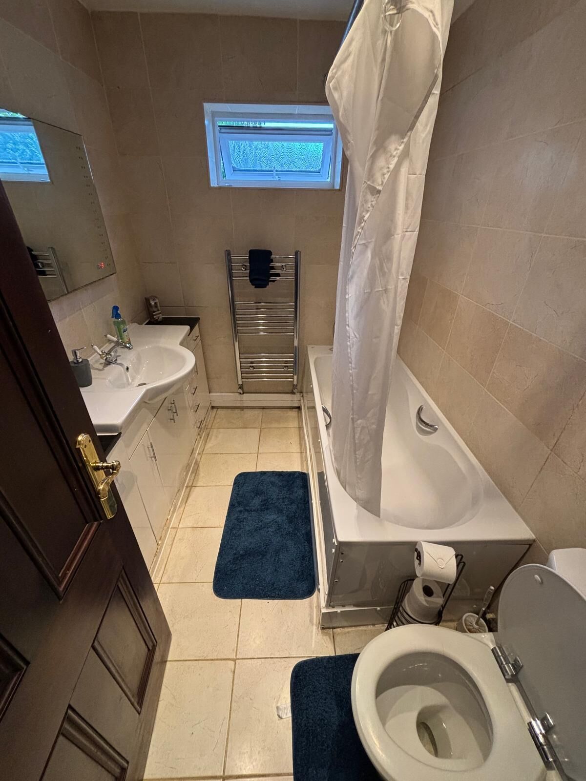A bathroom with a bathtub, toilet, sink, and a window above the sink.