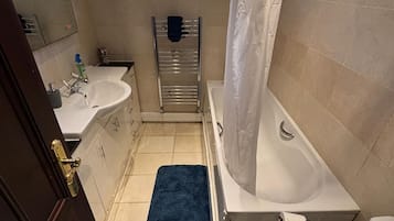 A bathroom with a bathtub, toilet, sink, and a window above the sink.