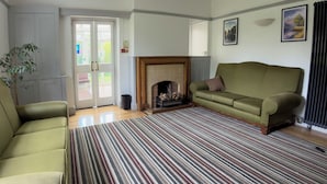 A living room with a sofa, a striped rug, a fireplace, and a door leading outside.