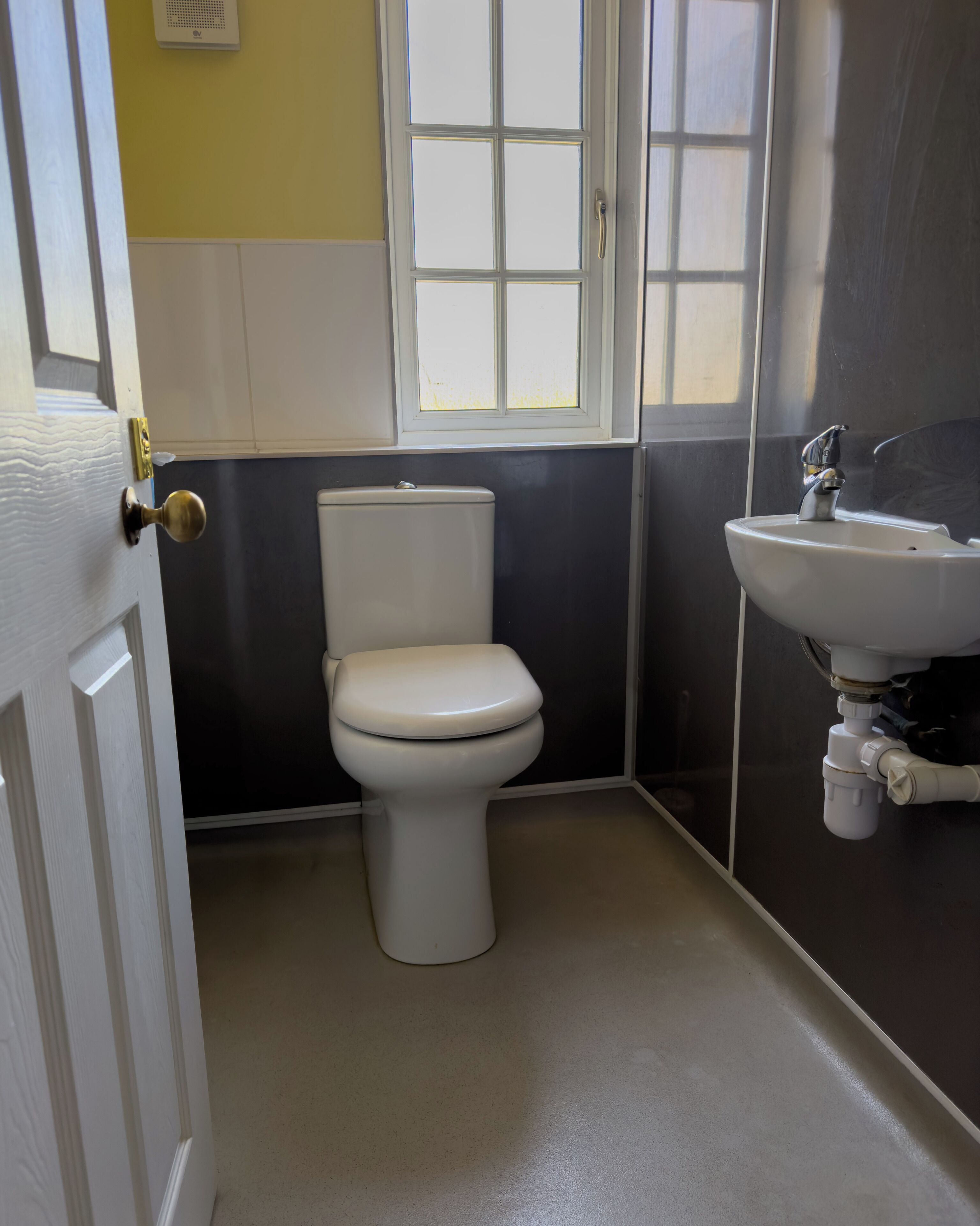 A bathroom with a toilet, sink, and a window.