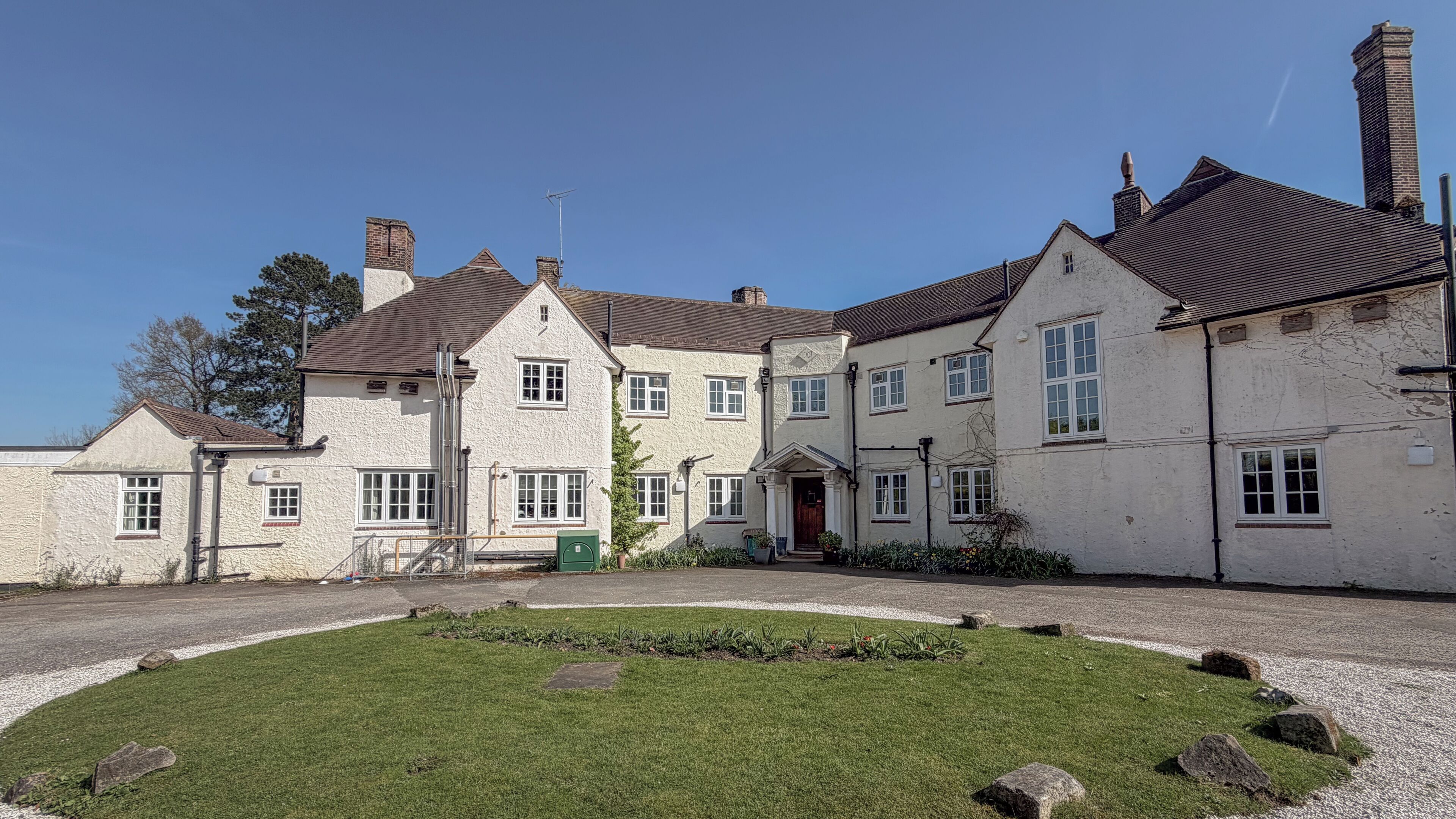 A traditional building with multiple windows and a well-maintained lawn.