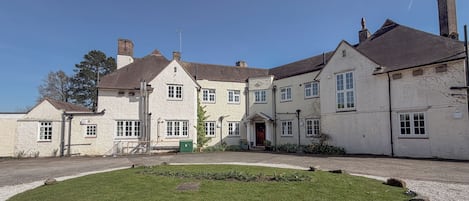 Un bâtiment traditionnel doté de nombreuses fenêtres et d’une pelouse bien entretenue.