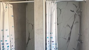 A shower area with a marble wall, a showerhead, and a curtain with a blue pattern.