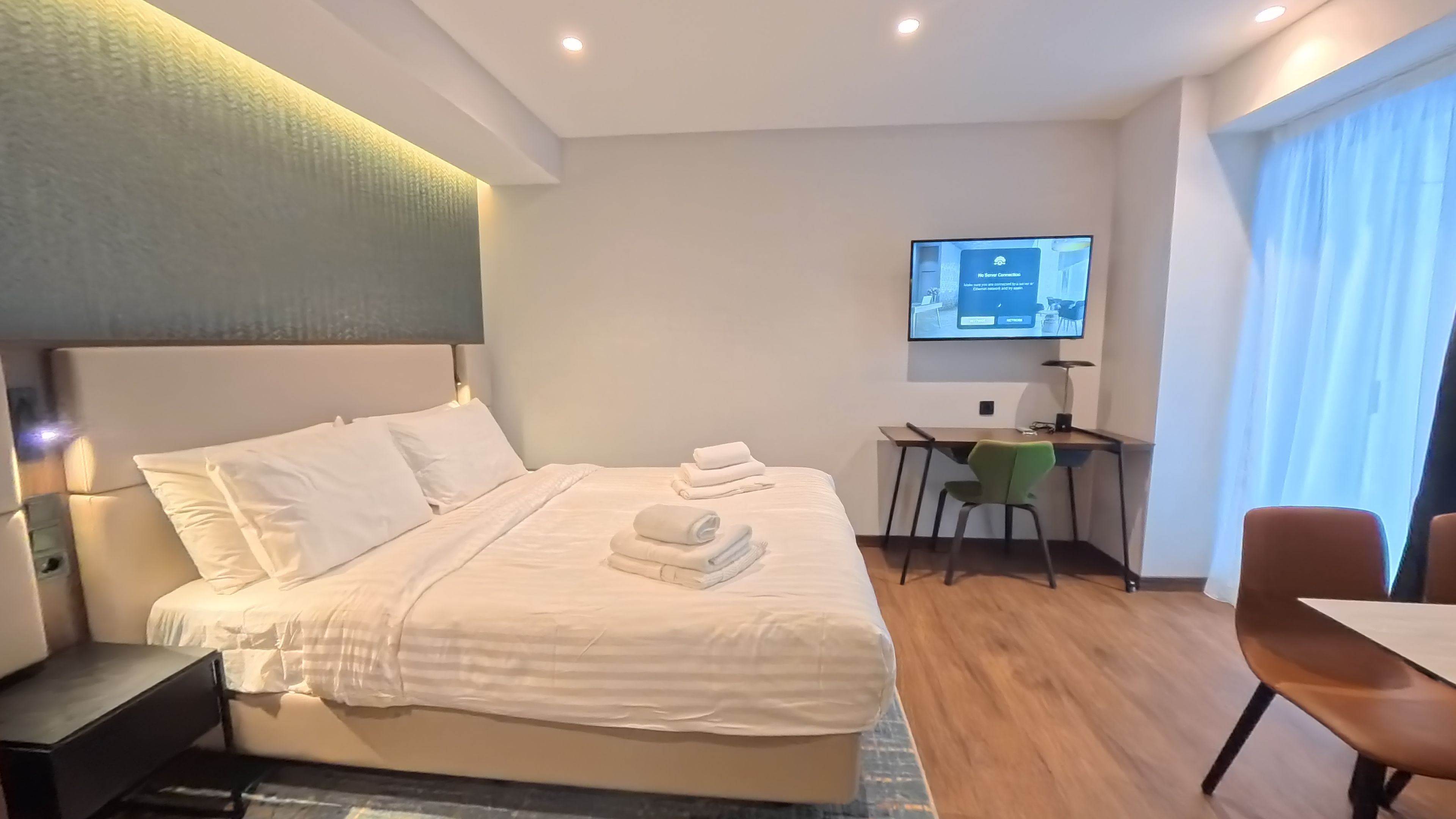 A hotel room with a bed, a desk, a chair, and a television.
