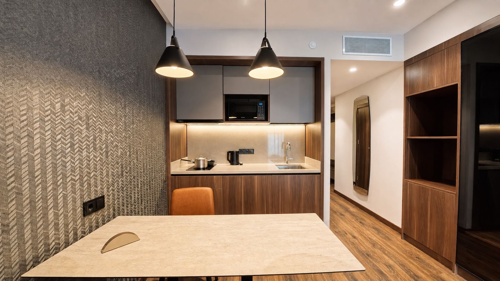 Una cocina moderna con una isla central, iluminación colgante y electrodomésticos integrados.