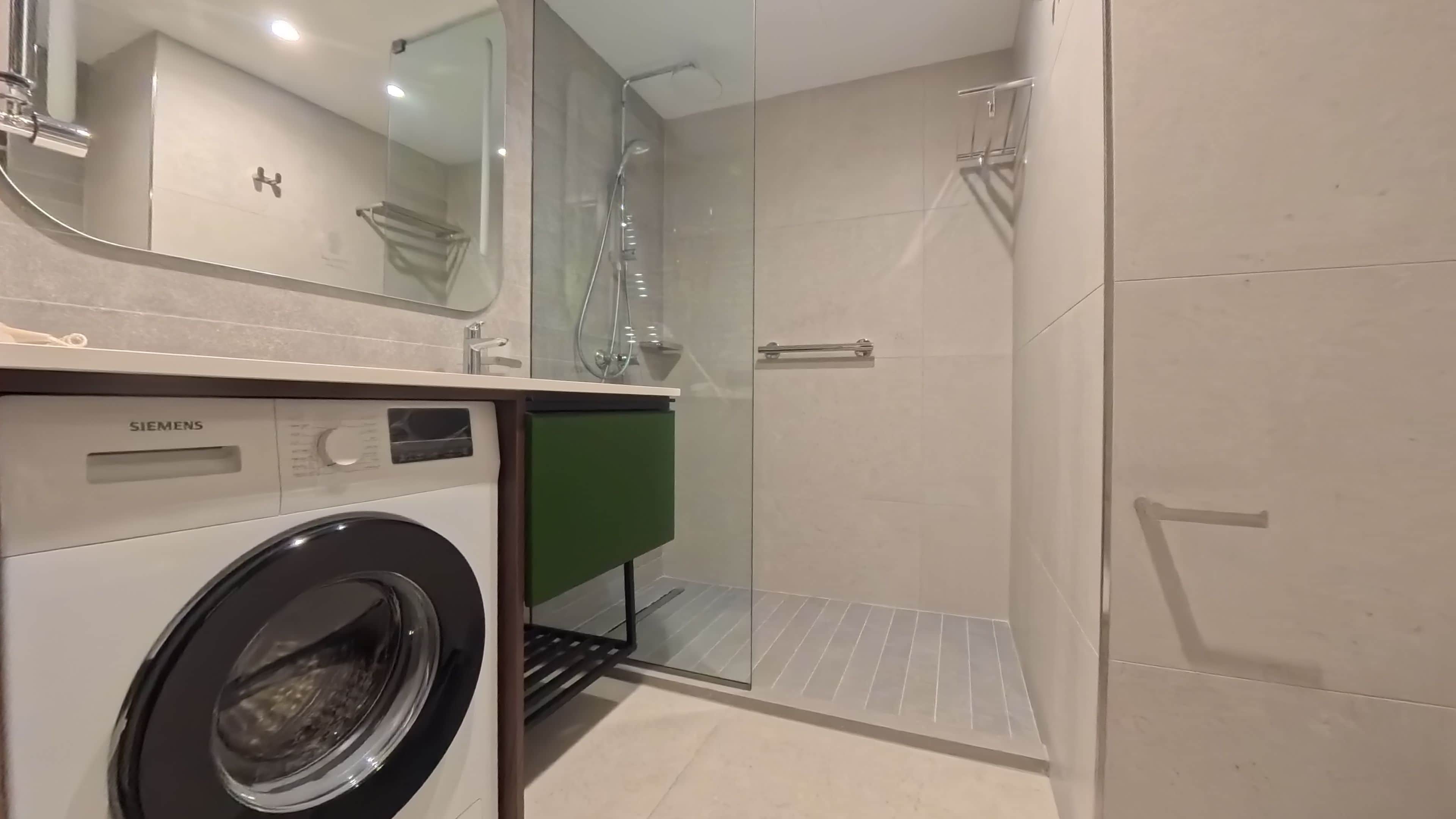 Ein modernes Badezimmer mit einer Siemens Waschmaschine, einer Duschkabine aus Glas und einem grünen Schrank.