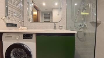 A modern bathroom with a washing machine, a sink, and a shower.