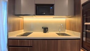 Una cocina moderna con microondas integrado, cafetera y pileta.