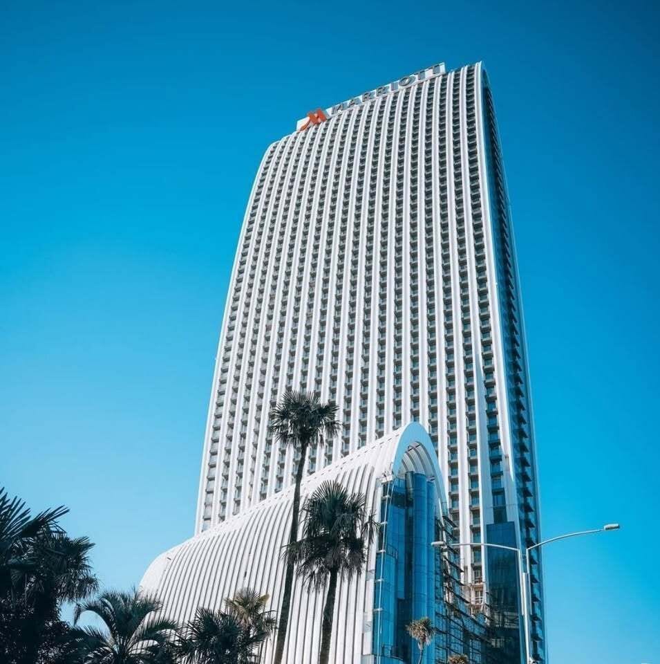 A tall, modern skyscraper with a distinctive curved glass facade and a series of vertical windows.