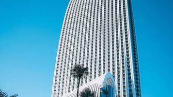 A tall, modern skyscraper with a distinctive curved glass facade and a series of vertical windows.
