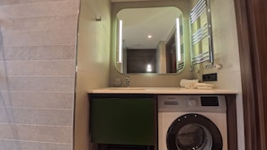 Un baño de hotel con lavamanos, espejo, toalla y lavadora.