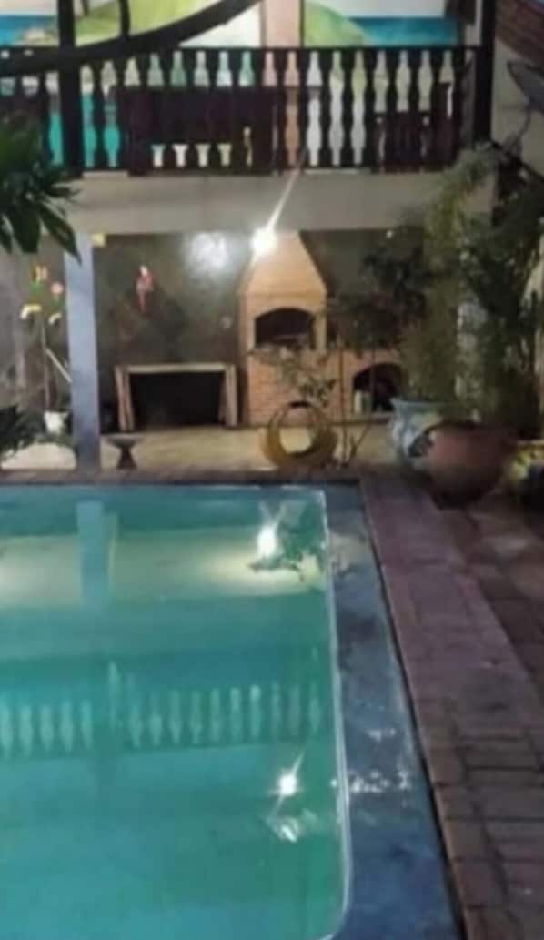 A swimming pool with a tiled deck, a brick wall, and a small outdoor grill area. - House in Saquarema, spacious with games room and gourmet area!!! (Saquarema)