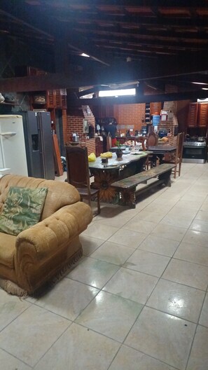 A spacious living area with a large sofa, a dining table, and a kitchen in the background. - House in Saquarema, spacious with games room and gourmet area!!! (Saquarema)