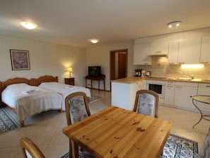 A hotel room with two beds, a dining table, and a kitchenette.
