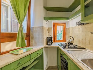 A kitchen with a green countertop, a coffee maker, a kettle, and a window with a curtain. - La Finestra sul Lago by Interhome (Porlezza)
