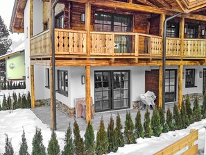 Ein zweistöckiges Holzhaus mit Balkonen, großen Fenstern und einem mit Schnee bedeckten Gelände.