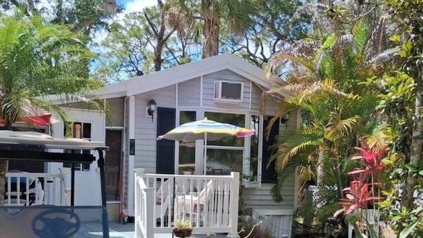 A residential property with a porch, a golf cart, and tropical vegetation.