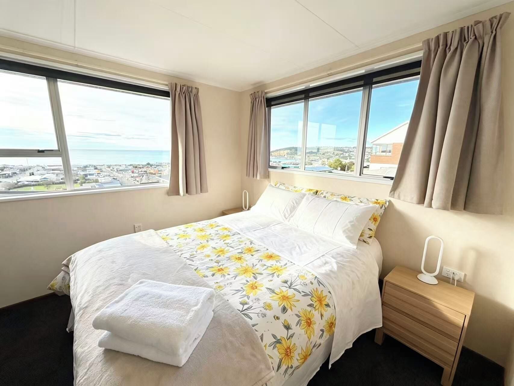 Camera d'albergo con un letto, un comodino, una lampada e vista sulla città.