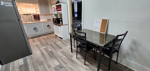 A compact kitchen with a refrigerator, microwave, and cabinets. There is a dining table with chairs.