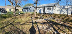 A residential area with multiple houses, a fenced yard, and a clear sky.