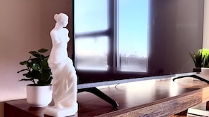Une statue posée sur une table en bois, avec une fenêtre en arrière-plan.