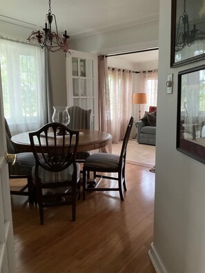 A dining area with a round table, chairs, and a chandelier. - Well-appointed 3-bedroom house, sleeps 8 with gorgeous sunsets! (Manistee)