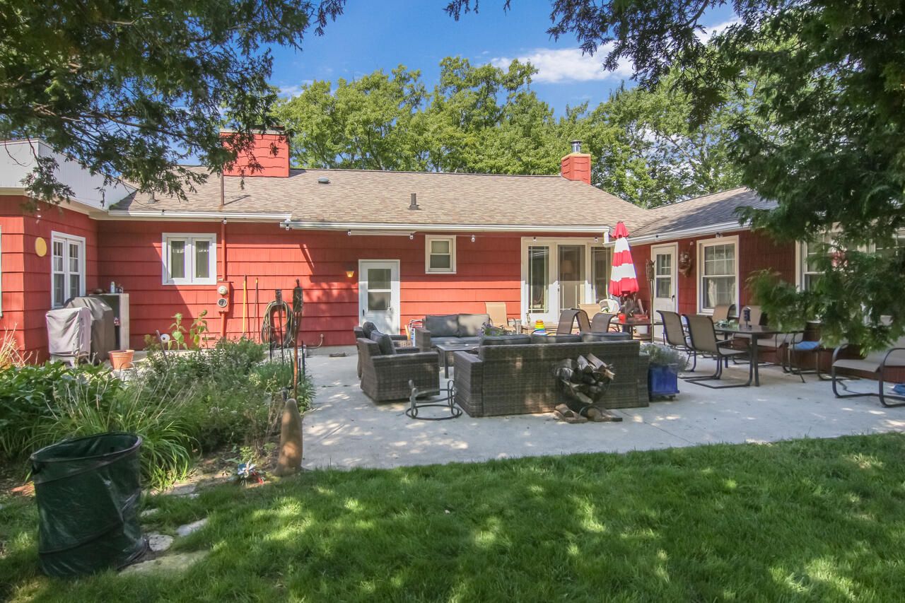 A red house with a patio, outdoor furniture, and a red and white umbrella.