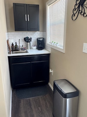 A compact kitchen with a sink, coffee maker, and cabinets.