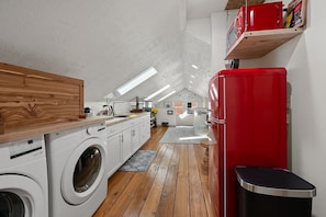 A compact kitchen with a washing machine, a red refrigerator, and a wooden countertop. - Luxurious Furnished Loft Suite - GREAT for Traveling Nurses/Students (Sioux Falls)