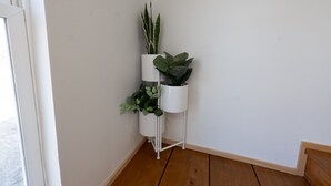 Eine Ecke mit einem weißen Pflanzenständer, der drei Blumentöpfe trägt.