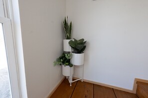 Eine Ecke mit einem weißen Pflanzenständer, der drei Blumentöpfe trägt.