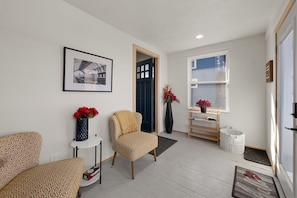 A modern living room with a sofa, armchair, and a small table with a vase of flowers. - Luxurious Furnished Loft Suite - GREAT for Traveling Nurses/Students (Sioux Falls)