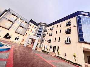 A multi-story building with balconies, a central courtyard, and a mix of window styles. - De New Dawn DND Hotel And Lounge  (Ife)