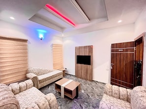 A modern living room with a sofa set, a coffee table, a TV mounted on the wall, and a wooden wardrobe. - De New Dawn DND Hotel And Lounge  (Ife)