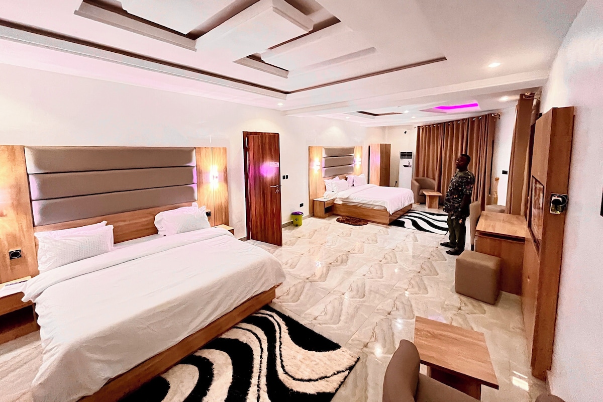 A hotel room with two beds, a seating area, and a mirror.