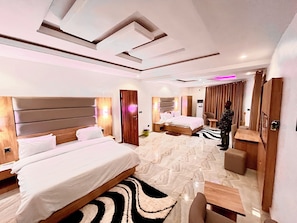 A hotel room with two beds, a seating area, and a mirror. - De New Dawn DND Hotel And Lounge  (Ife)