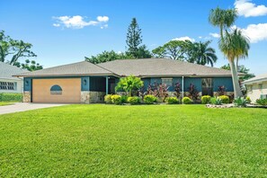 Ein Bungalow mit Garage, umgeben von einem gepflegten Rasen und verschiedenen Pflanzen.