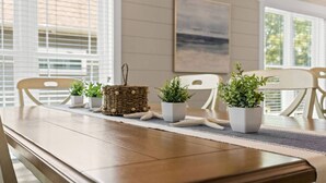 A dining table with chairs, potted plants, and a woven basket. - The Crabby Buffalo𓇼Golf Cart+Outdoor Oasis+Cozy (Oak Island)