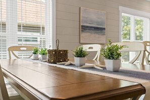 A dining table with chairs, potted plants, and a woven basket. - The Crabby Buffalo𓇼Golf Cart+Outdoor Oasis+Cozy (Oak Island)